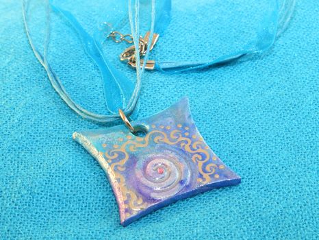 clay handmade blue amulet on a blue background