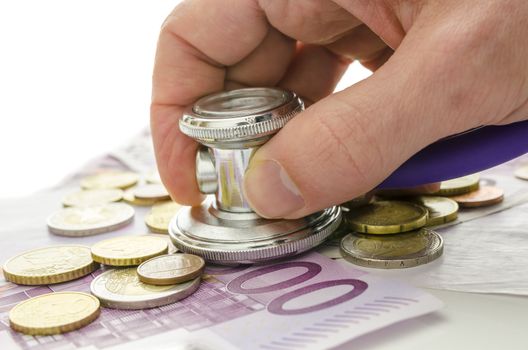 Male hand holding stethoscope on European currency. Concept of financial crisis solution.