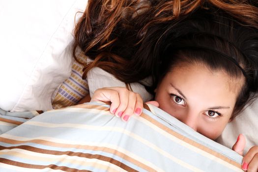 A young woman hiding under a blanket.