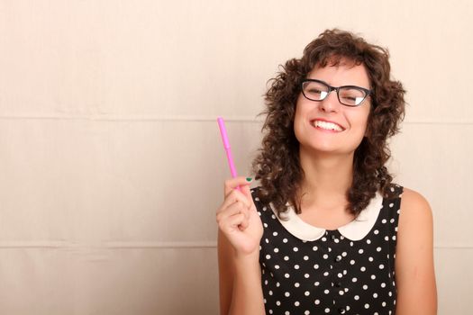 A young woman in a vintage dress holding a pen.