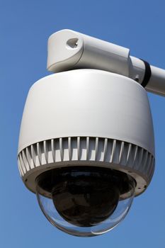 Outdoor security camera located against a blue sky background.