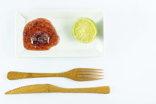 lime and strawberry preservers on a plate next to wooden fork and knife