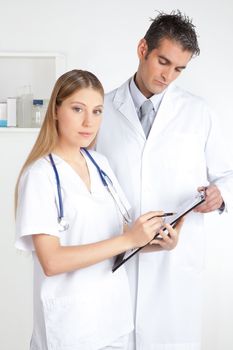 Female doctor showing clipboard to the male doctor.