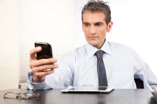 Businessman using cell phone at work in office.