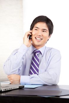 Asian businessman talking on cell phone at work .