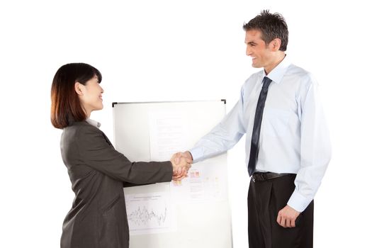 Smiling businesswoman and businessman shaking hand at presentation in office.