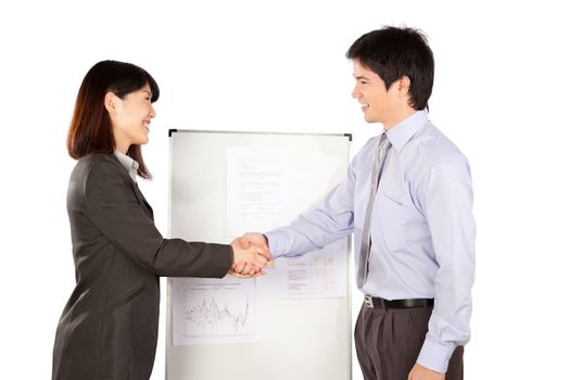 Smiling businesswoman and businessman shaking hand at presentation in office.