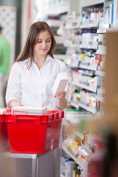 Female pharmacist in drugstore stocking shelves
