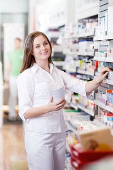 Portrait of female pharmacist standing in pharmacy drugstore with prescription paper