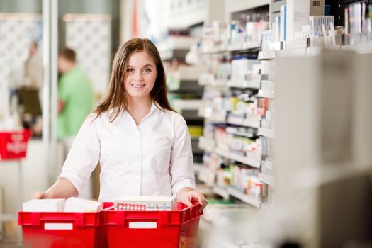 Attractive female pharmacist looking at camera in pharmacy setting.