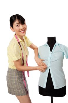 Young Asian woman dressmaker adjusting clothes on tailoring mannequin.