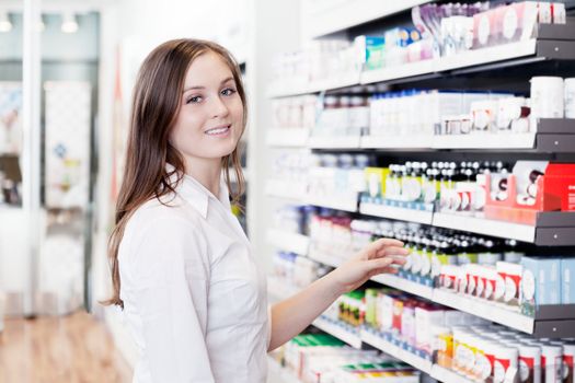 Portrait of young female pharmacist standing in pharmacy store