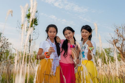 Asian Thai girls are standing together in the field.