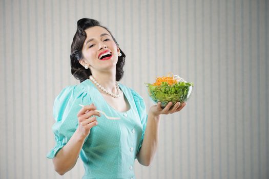 Portrait of a girl looking positive and holding a bowl with salad