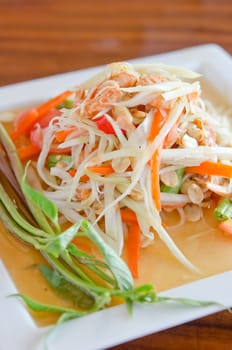 spicy papaya salad with peanut , dried shrimp and vegetable on white plate