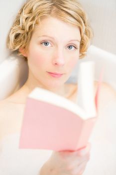 Young woman reading a book in the bath