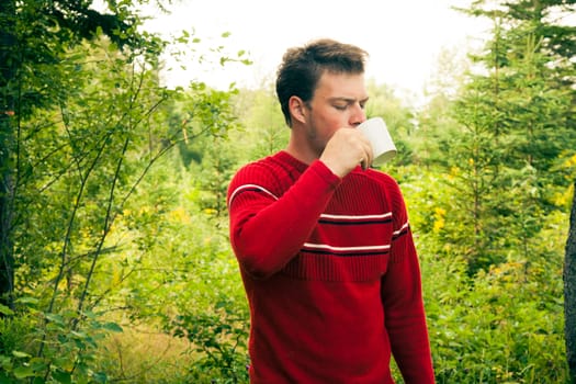 Man in nature drinking a mug of coffee