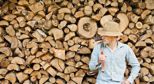 Woodcutter with straw hat on a background of wood