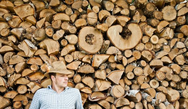 Woodcutter with straw hat on a background of wood taking a little break