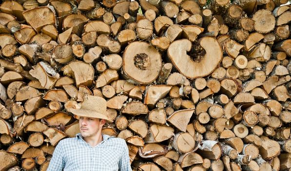 Woodcutter with straw hat on a background of wood taking a little break