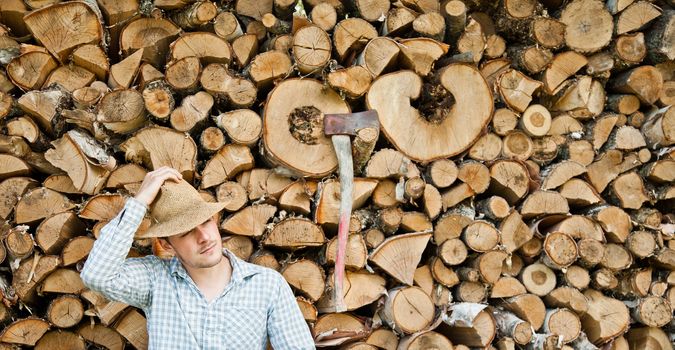 Woodcutter with straw hat on a background of wood taking a break