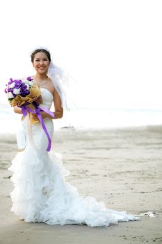 Lovely and beautiful bride with flower bouquet on the beach