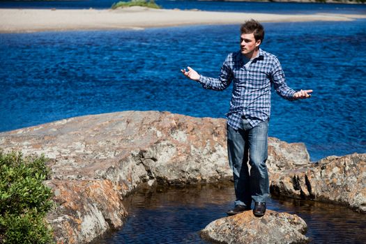 Young man stands on a rock in the middle of nowhere