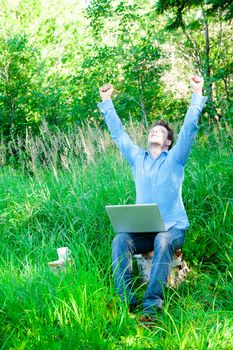 Young man outdoors with a laptop got a good news