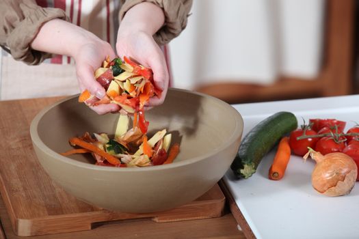 Woman putting vegetable peeling into bowl