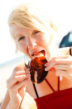 Girl eats lobster claw outdoor on a dinning table with sunlight