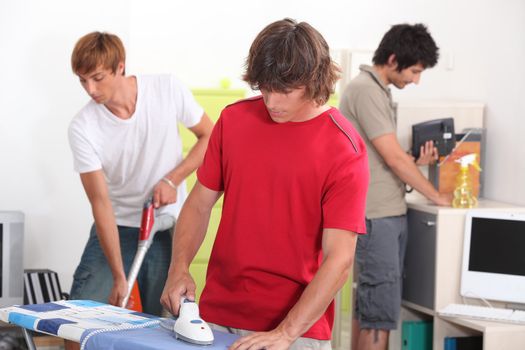 Three young male house-mates cleaning