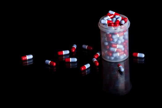 Container full of pills isolated on black background