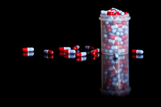 Container full of pills isolated on black background