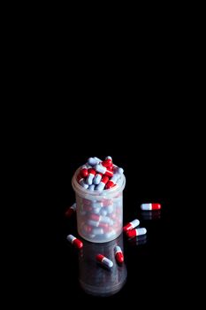Container full of pills isolated on black background