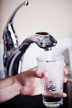 Thirsty man filling a glass of water