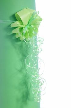 Decorative green ribbon and bow on a gift with long streamers hanging below on a white background with copyspace