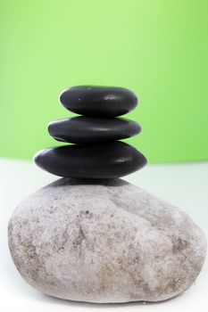 Three black stones stacked on top of a larger grey speckled stone.