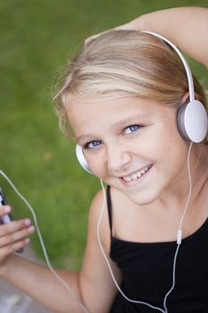 smiling child with smartphones and headphones looking at camera