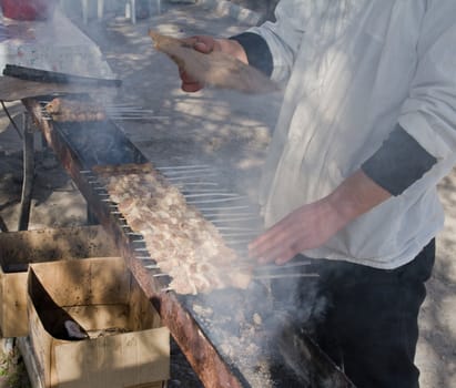 Man cook grilling meat on coal 