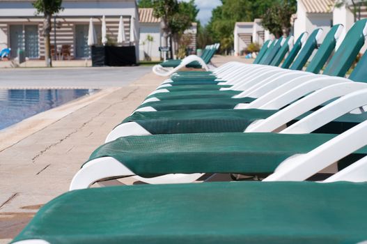 Blue swimming pool and chaise longues, summer
