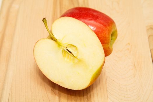 Fresh, red apple cut in half on a wood cutting board