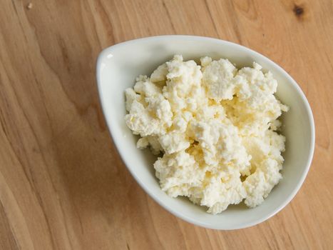 Homemade cottage cheese in a bowl on a cutting board