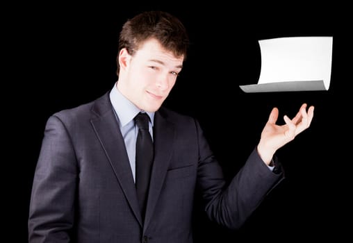 Businessman presenting a blank sheet of paper with room for text isolated on black