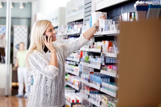 Female talking on cell phone while looking for medicines at drugstore