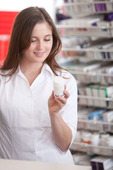 Portrait Of A Female Pharmacist At Pharmacy Reading Information On Medicine.
