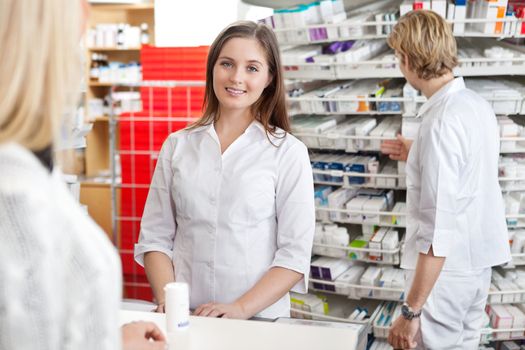 Pharmacist smiling while attending customer at counter