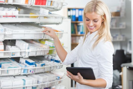 Female chemist standing in pharmacy drugstore with tablet PC
