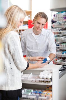 Male pharmacist helping female customer for medicine