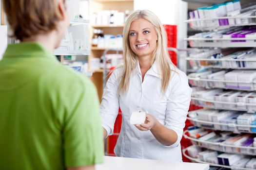 Female pharmacist giving medicine to customer at counter