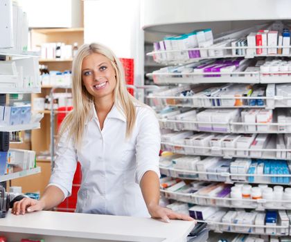 Portrait of smiling female pharmacist standing at checkout counter